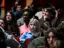 Un gruppo eterogeneo di giovani seduti in un auditorium che ascoltano attentamente una presentazione o un evento.