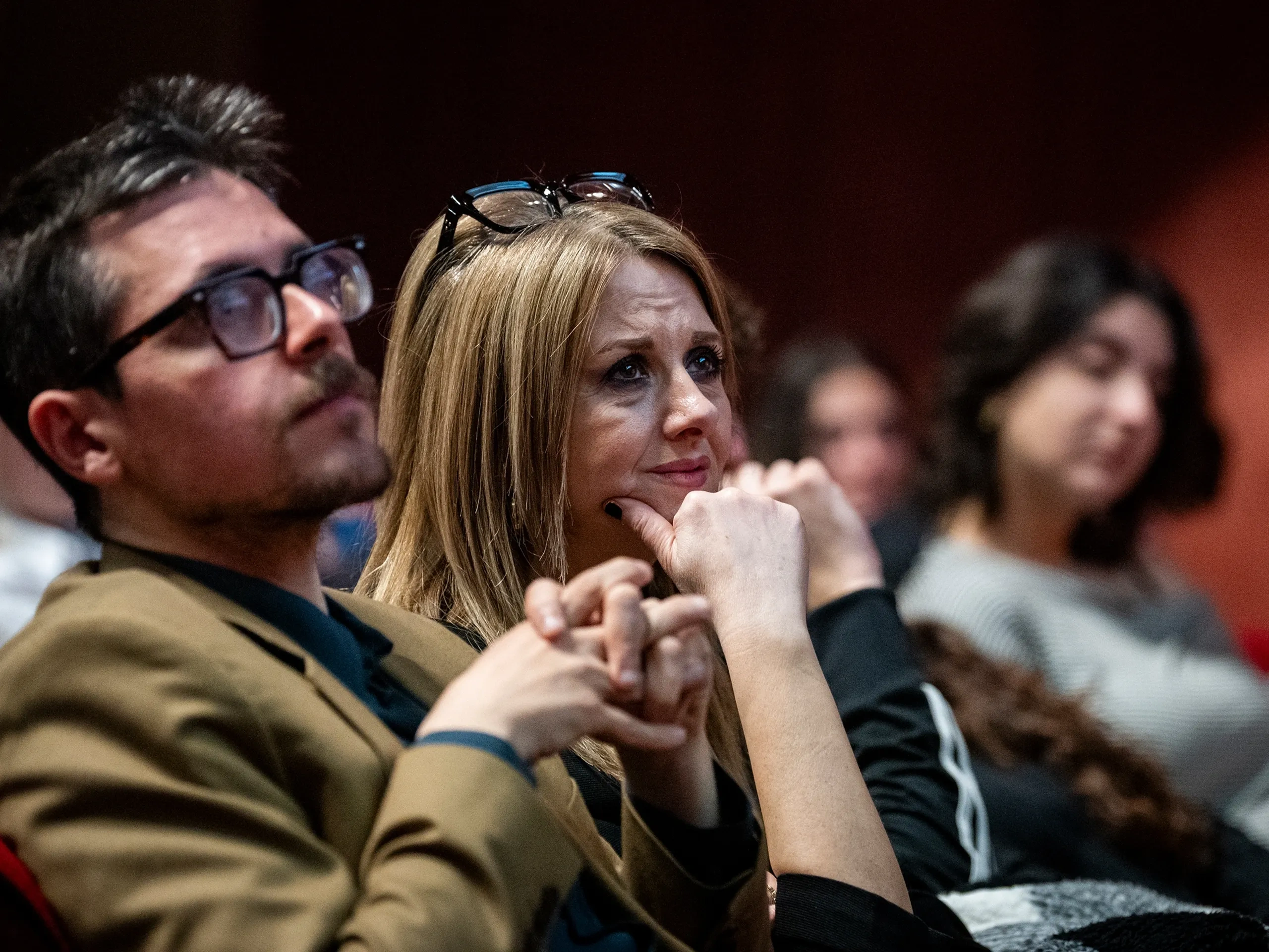 Il pubblico attento siede raggruppato, ascoltando con attenzione durante un evento al chiuso.
