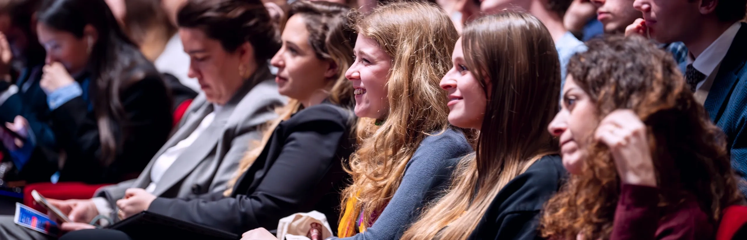 Audience members seated in a theater, attentively watching a presentation or performance.