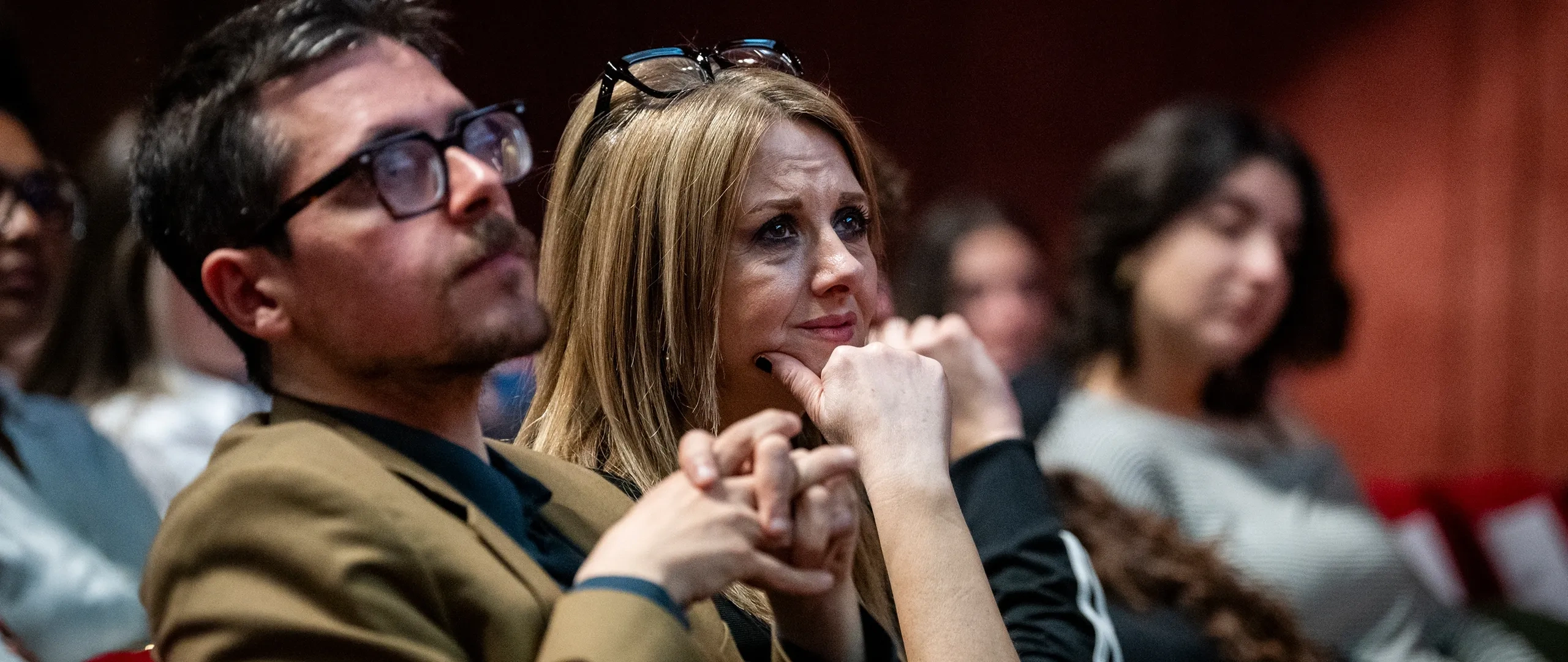 Il pubblico attento siede raggruppato, ascoltando con attenzione durante un evento al chiuso.